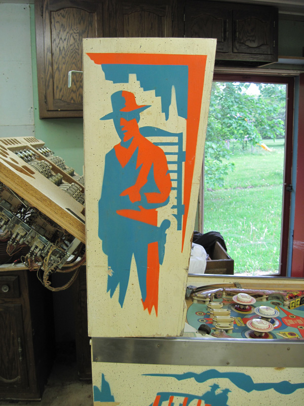 The upper side art, an image of a cowboy stenciled in orange and blue paint.